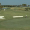 A view of a green protected by sand traps at Cocoa Beach Country Club with narrow road on the left